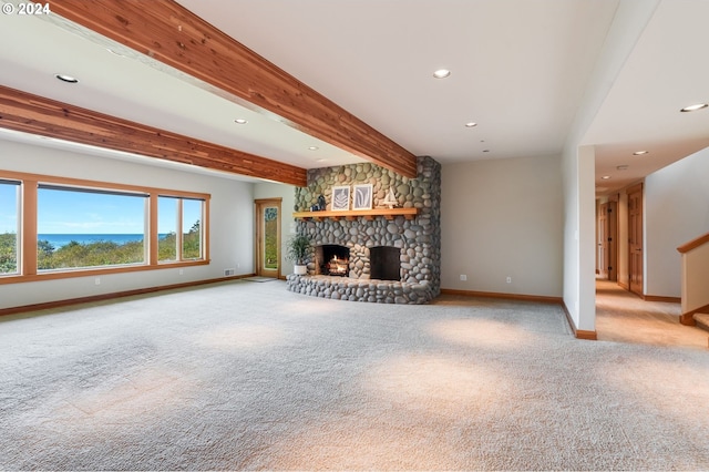 unfurnished living room with light carpet, beamed ceiling, and a fireplace