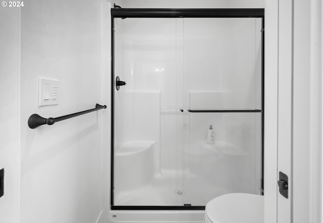 bathroom featuring an enclosed shower and toilet