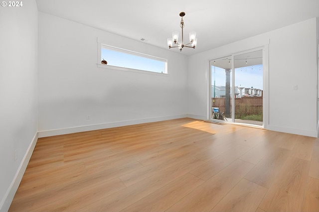 unfurnished room with a notable chandelier and light wood-type flooring