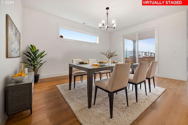 dining space with hardwood / wood-style flooring and a notable chandelier