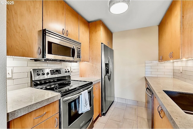 kitchen featuring sink, decorative backsplash, light tile patterned flooring, and appliances with stainless steel finishes