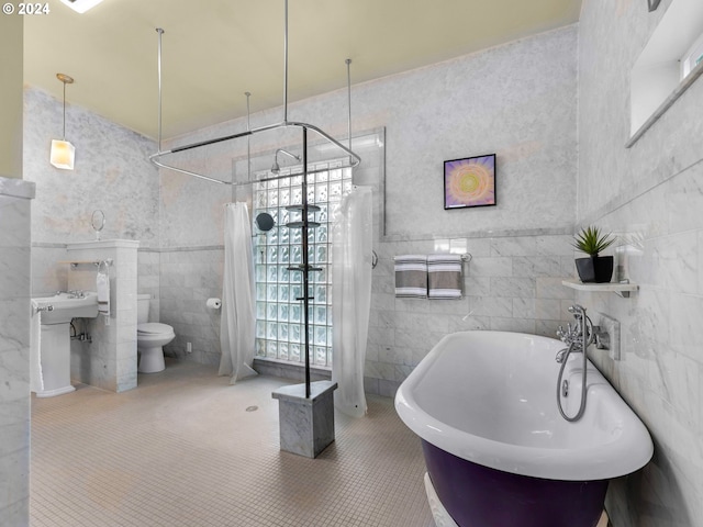 bathroom with a bathing tub, tile walls, tile patterned flooring, and toilet