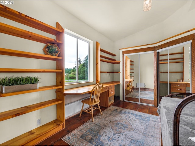 office area featuring lofted ceiling, radiator, built in desk, and dark wood-type flooring