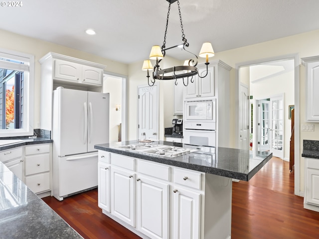 kitchen featuring a center island, white appliances, white cabinets, dark hardwood / wood-style floors, and decorative light fixtures