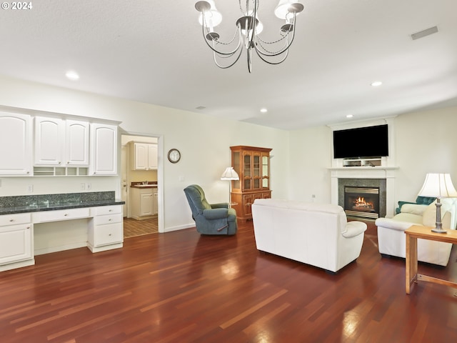 living room featuring built in desk, dark wood-type flooring, and a notable chandelier