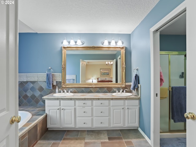 bathroom featuring a textured ceiling, vanity, separate shower and tub, and backsplash