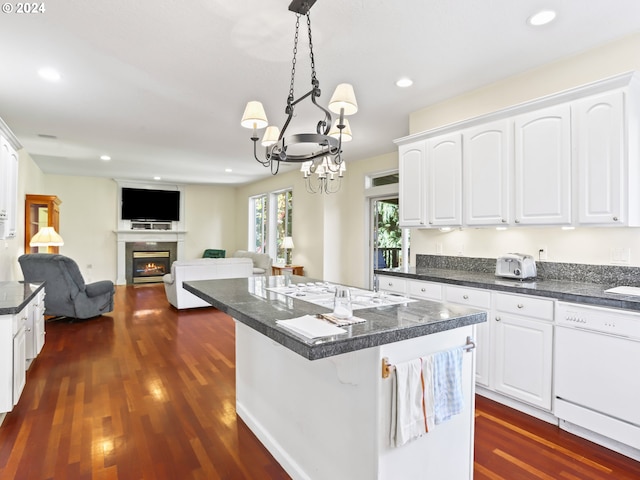 kitchen with white appliances, dark wood-type flooring, pendant lighting, white cabinets, and a center island