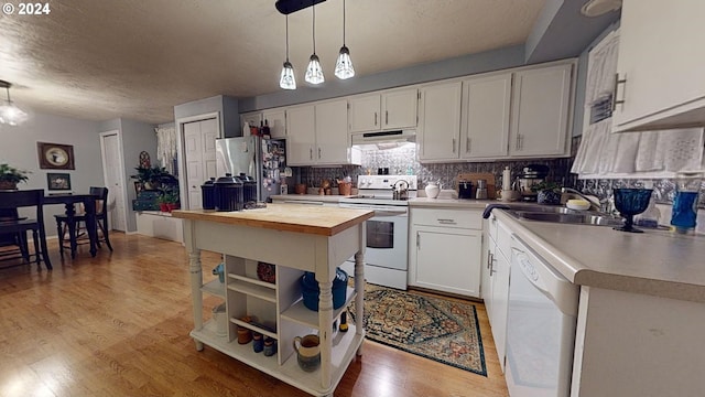 kitchen with light hardwood / wood-style floors, white cabinets, sink, white appliances, and decorative light fixtures