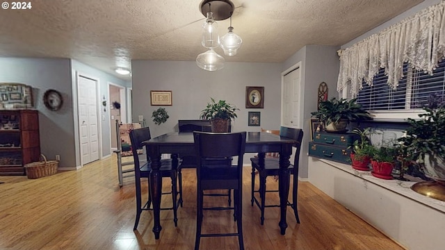 dining room with a textured ceiling, wood finished floors, and baseboards