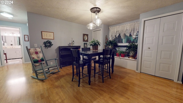 dining area featuring light wood-type flooring and a textured ceiling