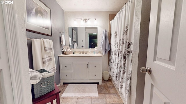 bathroom with a textured wall, vanity, baseboards, and curtained shower
