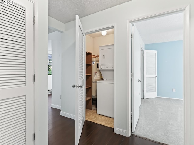 corridor with dark hardwood / wood-style flooring, stacked washer / drying machine, strapped water heater, and a textured ceiling