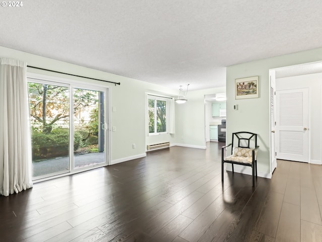 unfurnished living room featuring a baseboard heating unit, dark hardwood / wood-style floors, and a textured ceiling