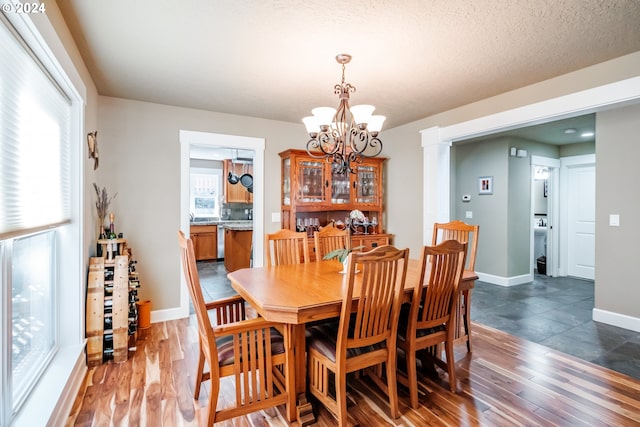 dining room with a chandelier, plenty of natural light, dark wood-type flooring, and a textured ceiling