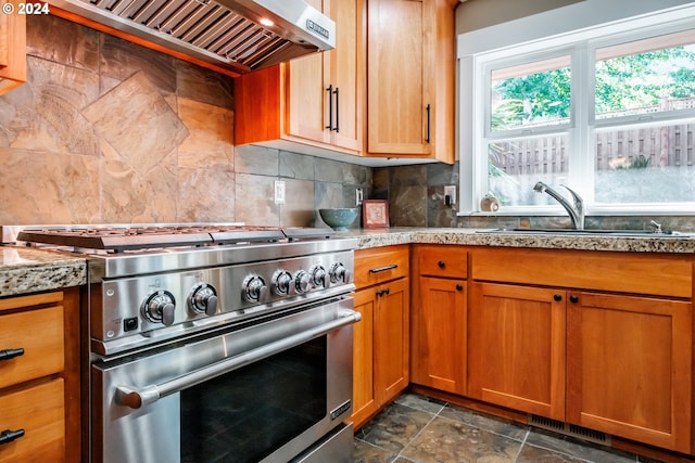 kitchen with high end stove, backsplash, range hood, and sink