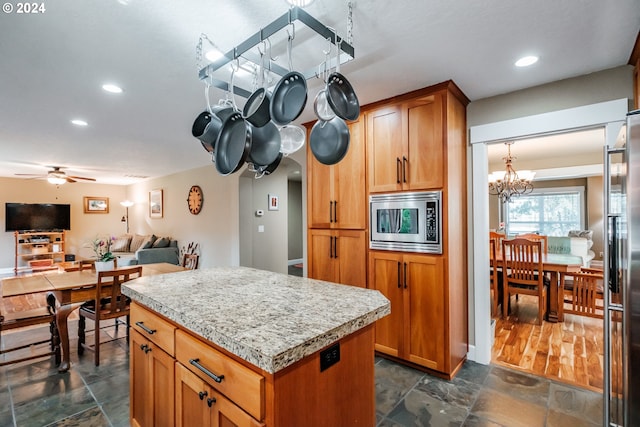 kitchen with a kitchen island, dark wood-type flooring, ceiling fan with notable chandelier, and appliances with stainless steel finishes