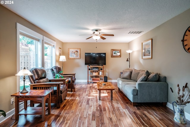 living room with ceiling fan, dark hardwood / wood-style flooring, and a textured ceiling