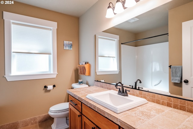 bathroom featuring plenty of natural light, toilet, a shower, and vanity