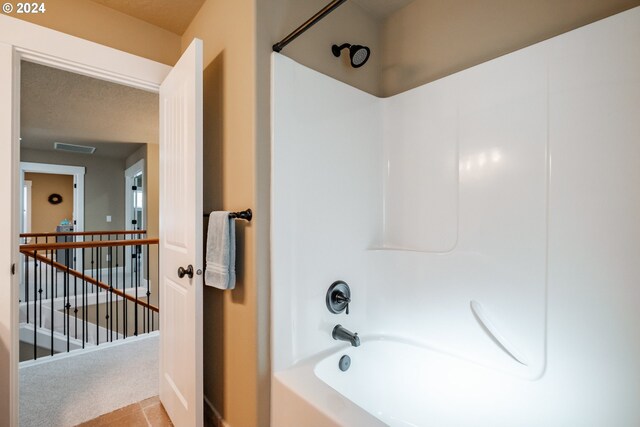 bathroom with shower / tub combination, tile patterned floors, and a textured ceiling