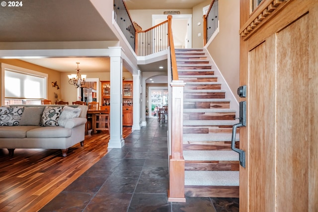 entrance foyer with ornate columns, dark wood-type flooring, and a chandelier