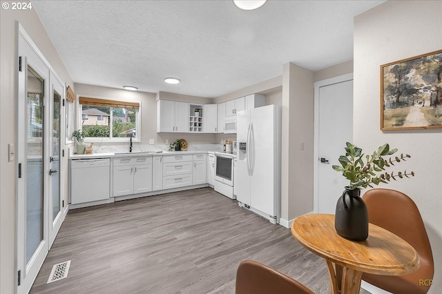 kitchen featuring white appliances, white cabinetry, sink, and light hardwood / wood-style flooring