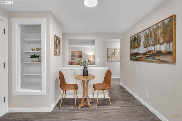 living area featuring dark wood-type flooring and built in shelves