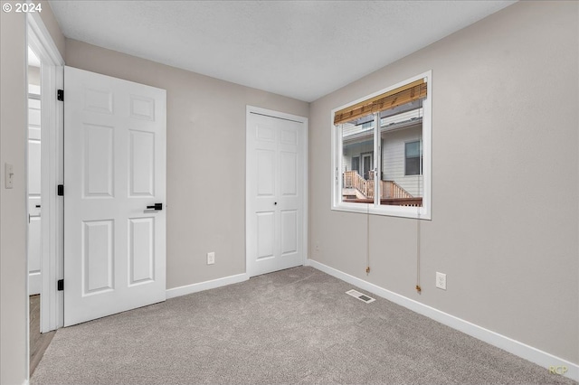 unfurnished bedroom featuring light carpet and a closet