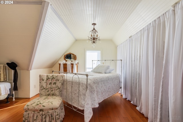 bedroom with vaulted ceiling, hardwood / wood-style flooring, and a notable chandelier