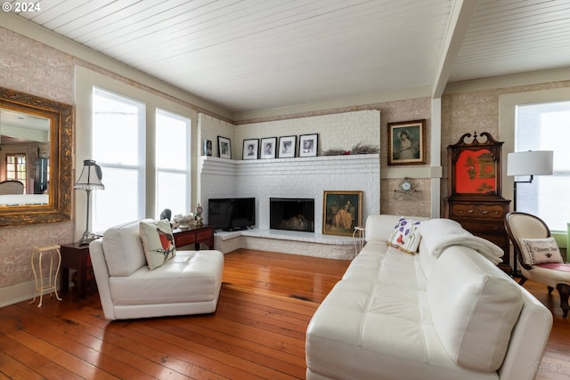 living room with beam ceiling, wood ceiling, hardwood / wood-style flooring, and a brick fireplace