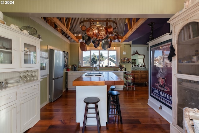 kitchen featuring stainless steel appliances, wooden counters, a kitchen island, white cabinets, and a breakfast bar area