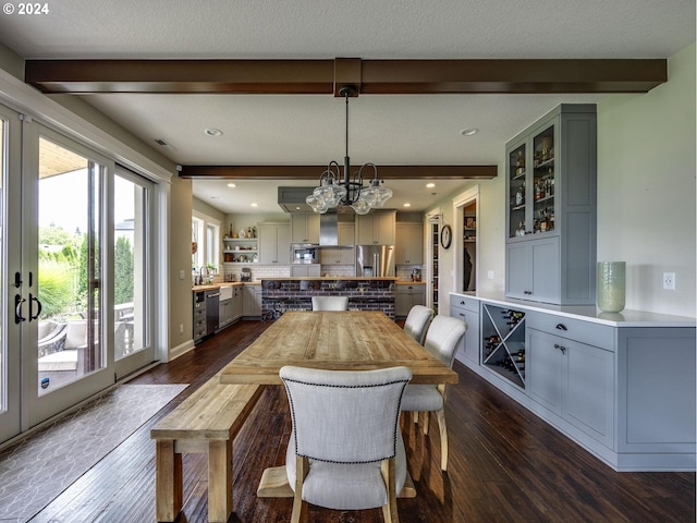 dining space featuring a textured ceiling, dark wood-type flooring, a chandelier, and beam ceiling