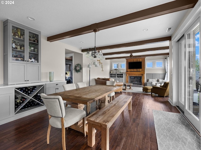 dining area featuring dark hardwood / wood-style floors, beamed ceiling, a healthy amount of sunlight, and a textured ceiling