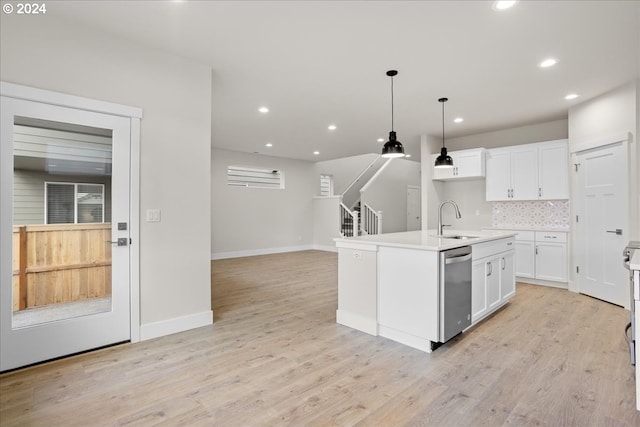 kitchen featuring white cabinetry, dishwasher, sink, hanging light fixtures, and a kitchen island with sink