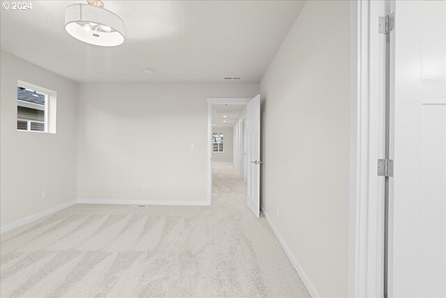 empty room with a textured ceiling, light colored carpet, and a healthy amount of sunlight