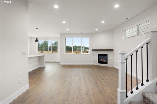 unfurnished living room featuring light wood-type flooring and a tiled fireplace