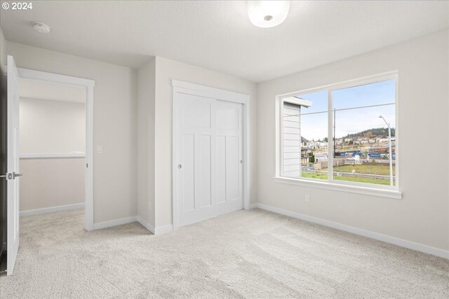 unfurnished bedroom featuring light colored carpet and a closet