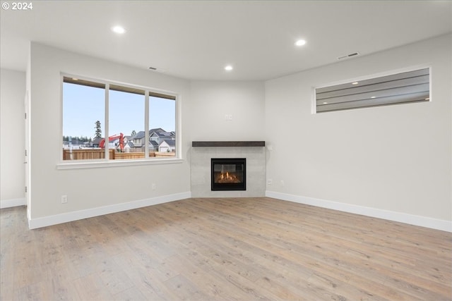 unfurnished living room with light hardwood / wood-style floors and a tile fireplace