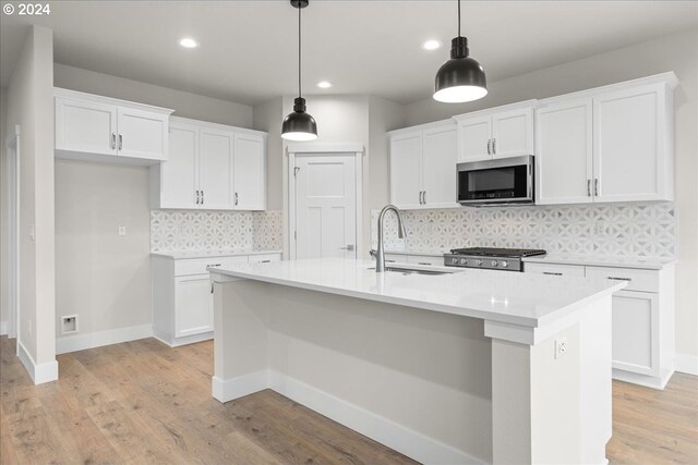 kitchen with pendant lighting, white cabinets, an island with sink, and appliances with stainless steel finishes