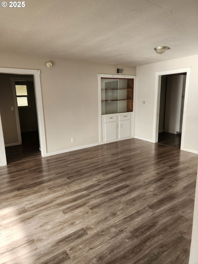 unfurnished living room featuring dark hardwood / wood-style flooring and a textured ceiling