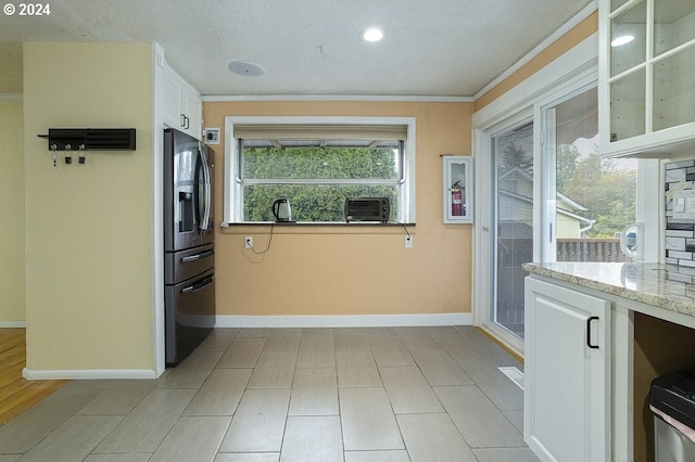 kitchen featuring light stone countertops, stainless steel fridge with ice dispenser, white cabinets, baseboards, and glass insert cabinets