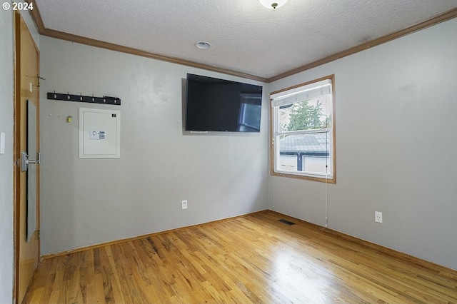 empty room with ornamental molding, hardwood / wood-style floors, and a textured ceiling