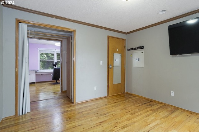 spare room with a textured ceiling, ornamental molding, and light wood-type flooring