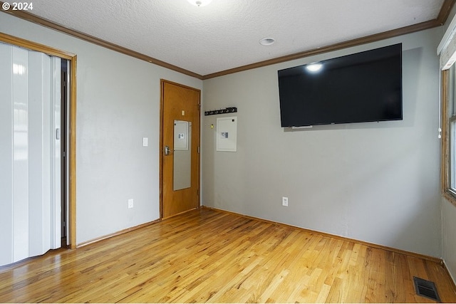 spare room with light hardwood / wood-style flooring, a textured ceiling, and crown molding