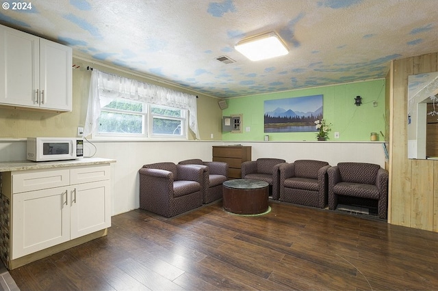 interior space with wooden walls, dark wood-style flooring, a textured ceiling, and visible vents
