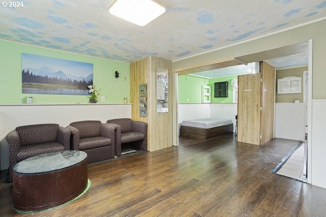 living room featuring wood walls, a textured ceiling, electric panel, and dark wood-type flooring