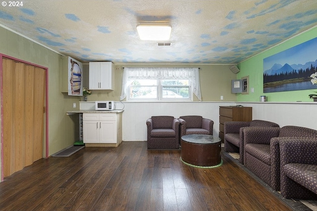 living room featuring wood walls, dark hardwood / wood-style floors, a textured ceiling, and crown molding