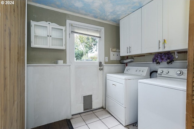 clothes washing area featuring ornamental molding, light tile patterned flooring, washer and dryer, and cabinets