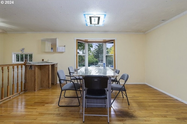 dining room featuring crown molding, a textured ceiling, and light wood-type flooring