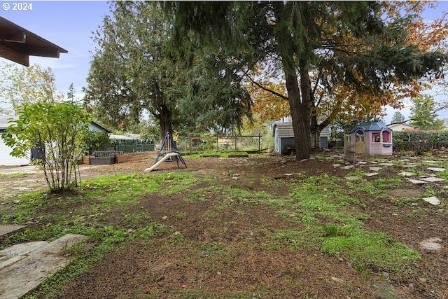 view of yard with a storage shed and a playground