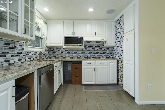 kitchen with white cabinets, stainless steel appliances, sink, and light stone counters